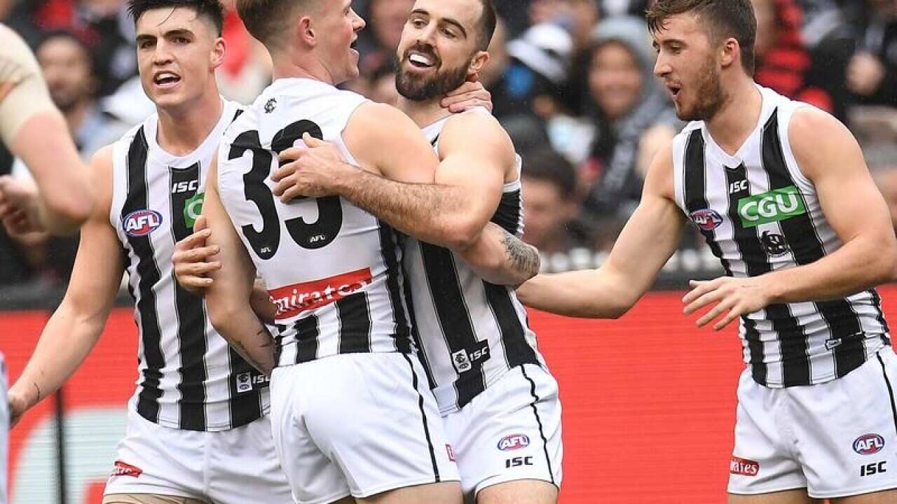 Steele Sidbottom of the Magpies (2R) celebrates after kicking a goal