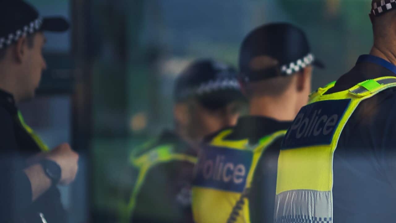 A group of police officers wearing hi-vis uniforms that say "Police" on the back.