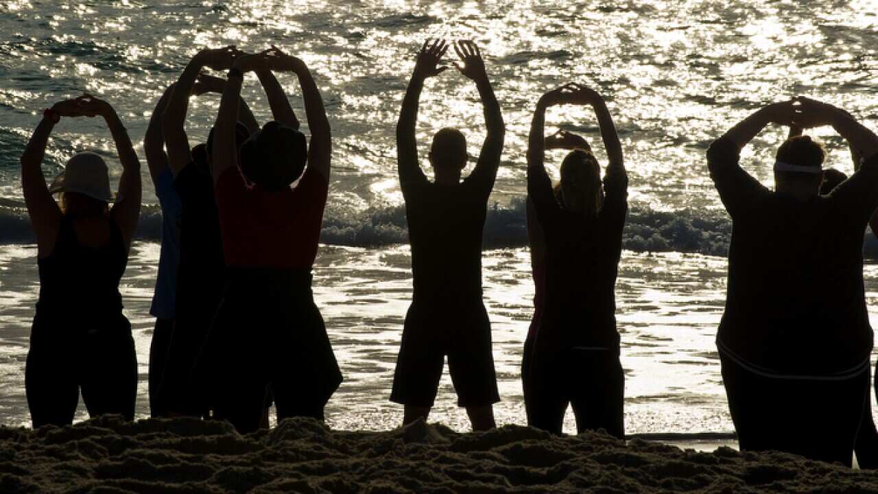 People face the ocean as they stretch during a Tai Chi exercise session at Currumbin Beach on the Gold Coast, Monday, Sep. 16, 2013. (AAP Image/Dave Hunt) NO ARCHIVING
