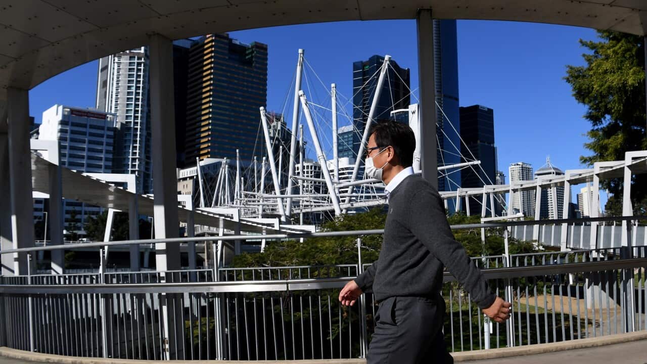 A man walks across the Kurilpa Bridge in Brisbane