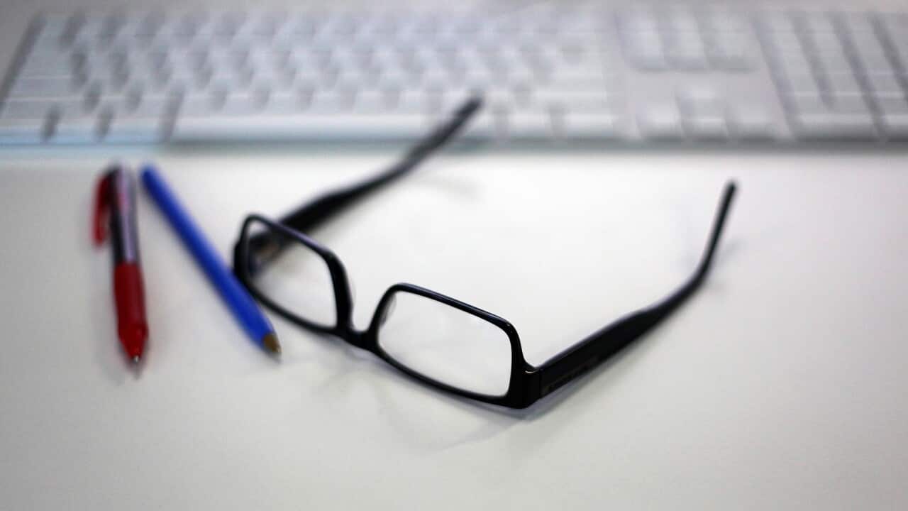 Reading glasses is featured alongside a Macintosh keyboard and office supplies in a stock image in Sydney, Wednesday, Jan. 13, 2016. (AAP Image/Sam Mooy) NO ARCHIVING