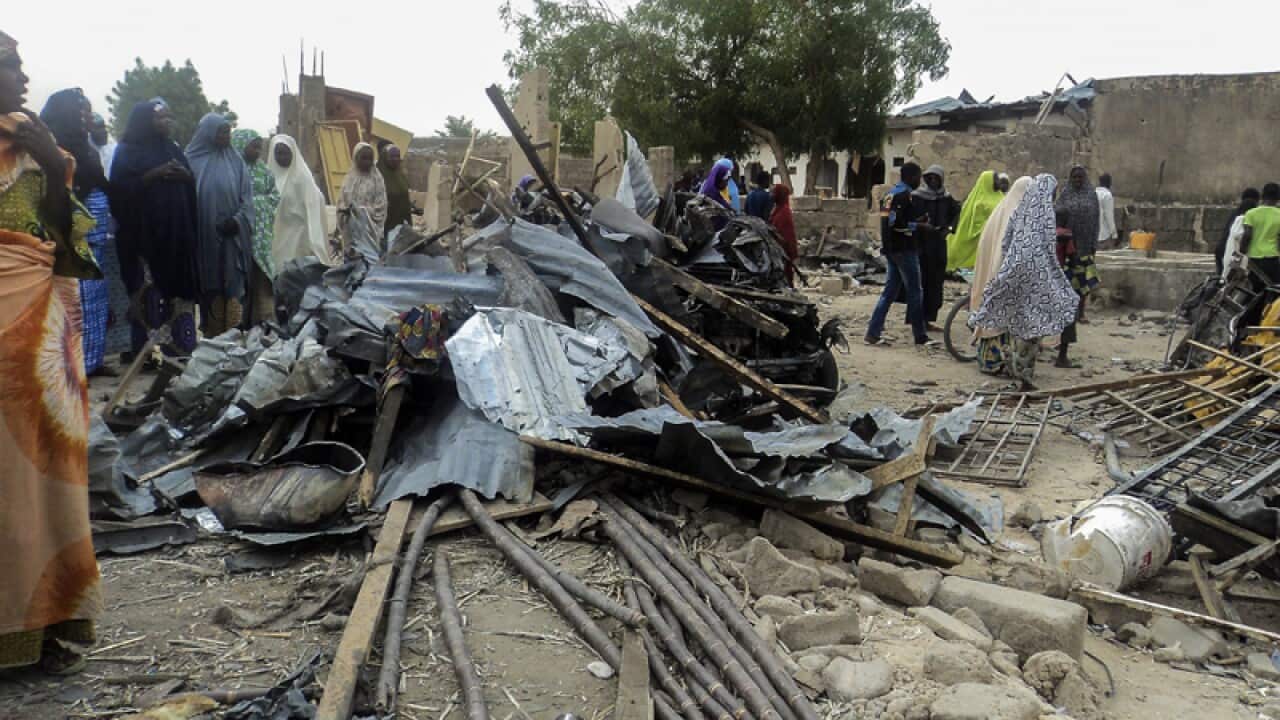 Nigerians look on at damage from a bomb in Maiduguiri, Nigeria