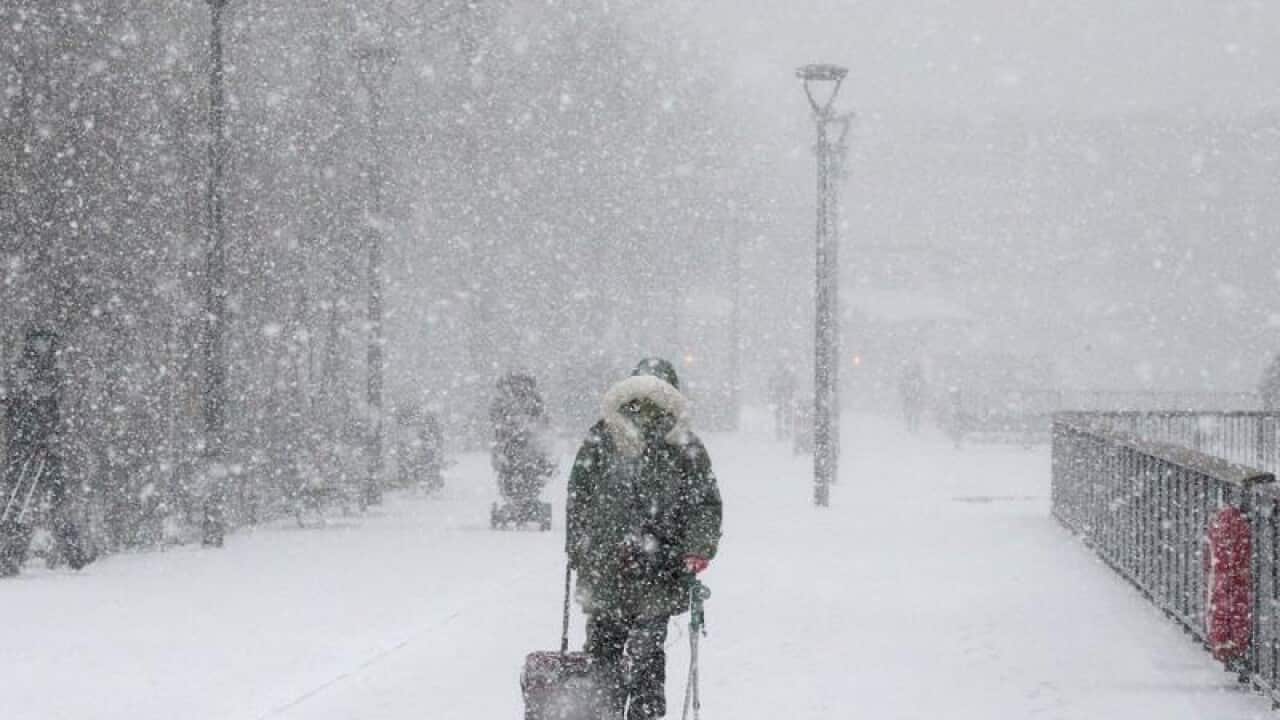 People walk along Bankside in the snow.