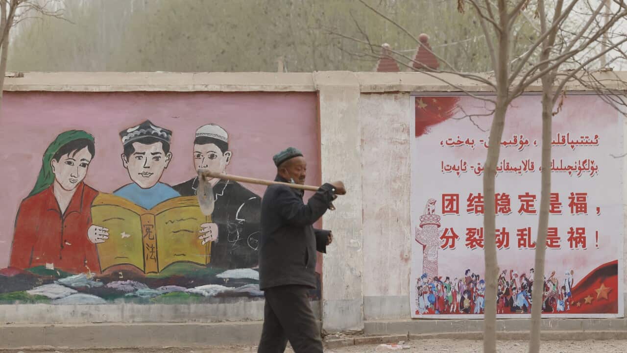 A farmer walks past government propaganda depicting ethnic minority residents reading the constitution with slogans which reads, "Unity Stability is fortune, Separatism and Turmoil is misfortune," near Kashgar in northwestern China's Xinjiang Uyghur Auton