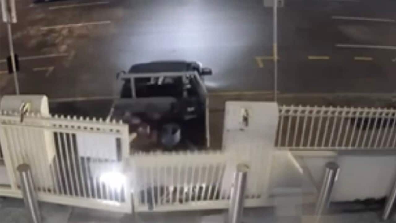 A still from CCTV footage showing a ute backing into a white gate