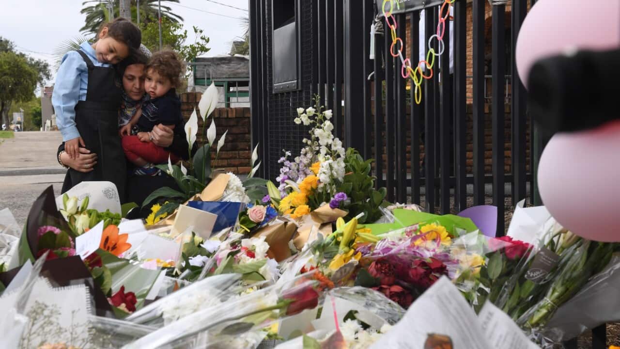 A mother and her young children place flowers outside the Banksia Road Public School in Greenacre, Sydney, Wednesday, November, 8, 2017.