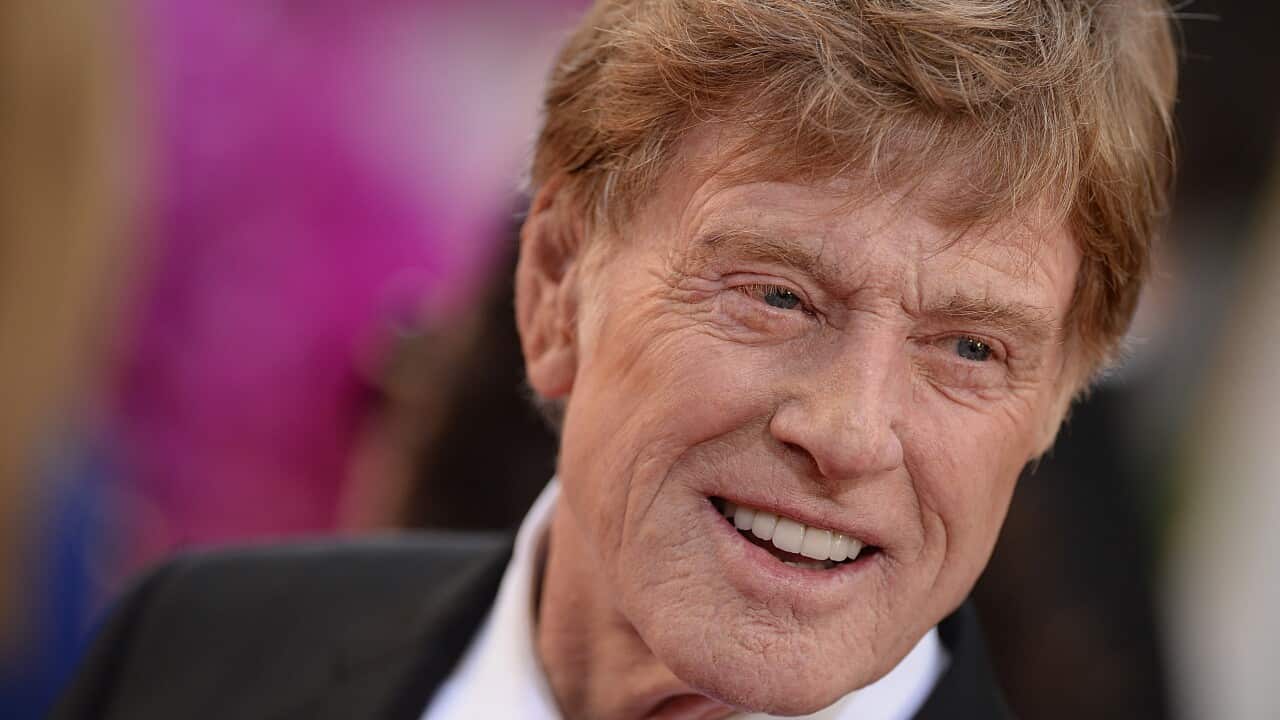 A close image of a man smiling wearing a dark suit