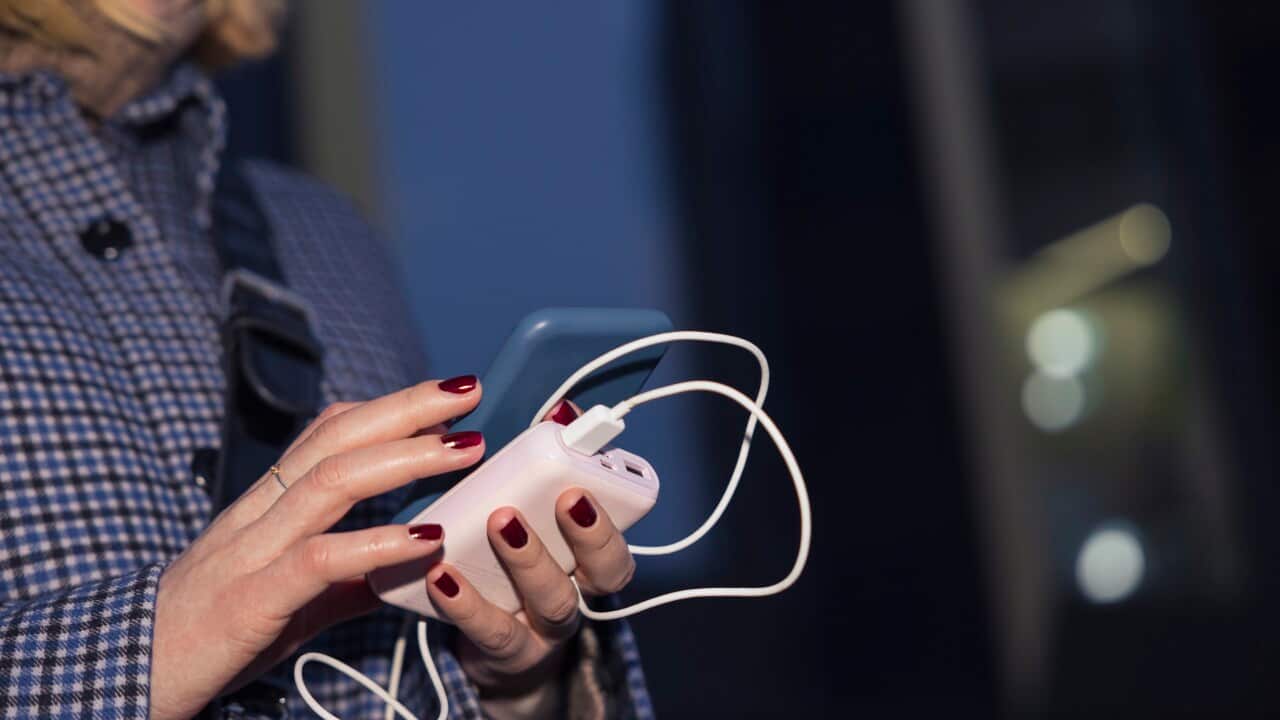 Young woman using phone and power bank outdoors