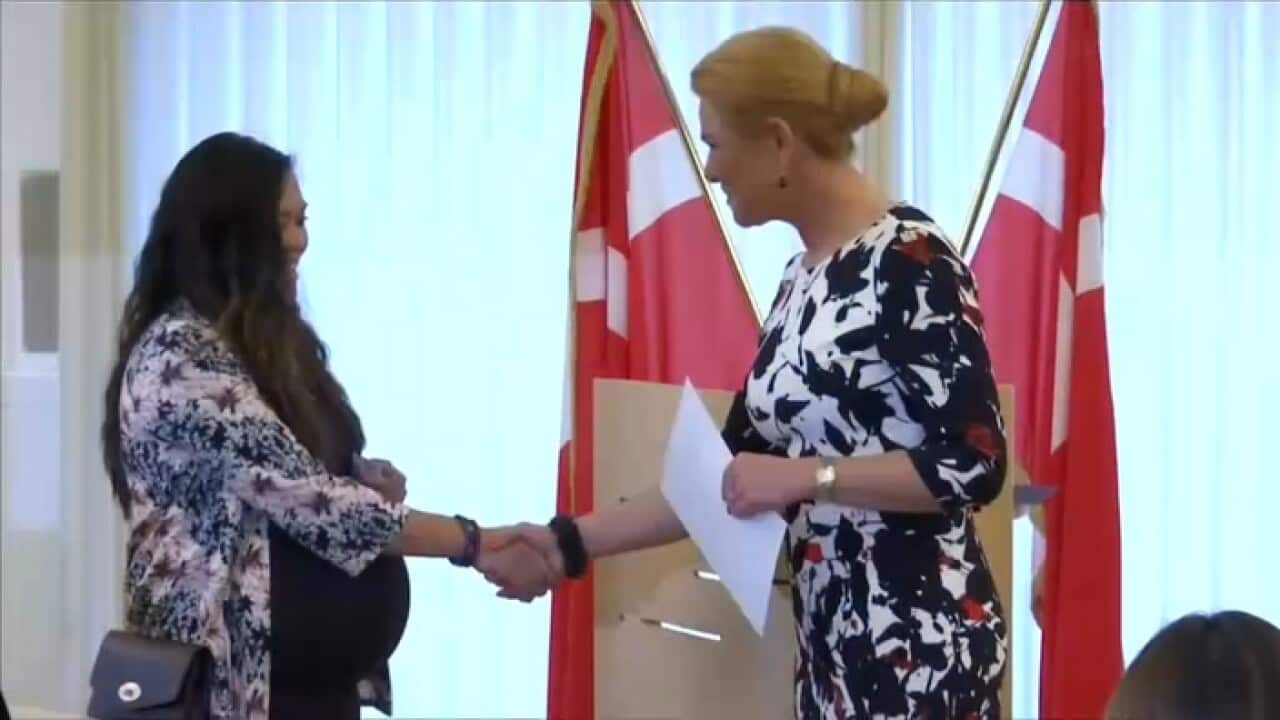 Denmark's Immigration Minister Inger Stojberg shakes hands with a new citizen