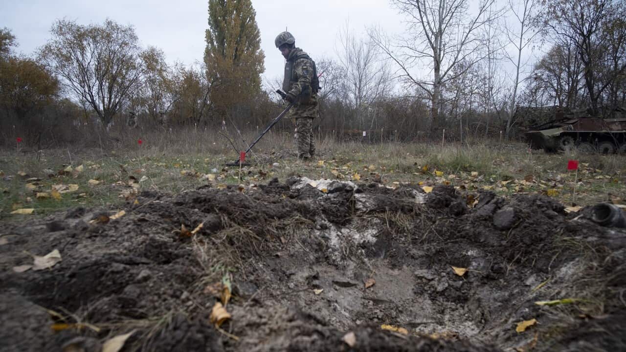 A Ukrainian soldier holds a metal detector to find landmines