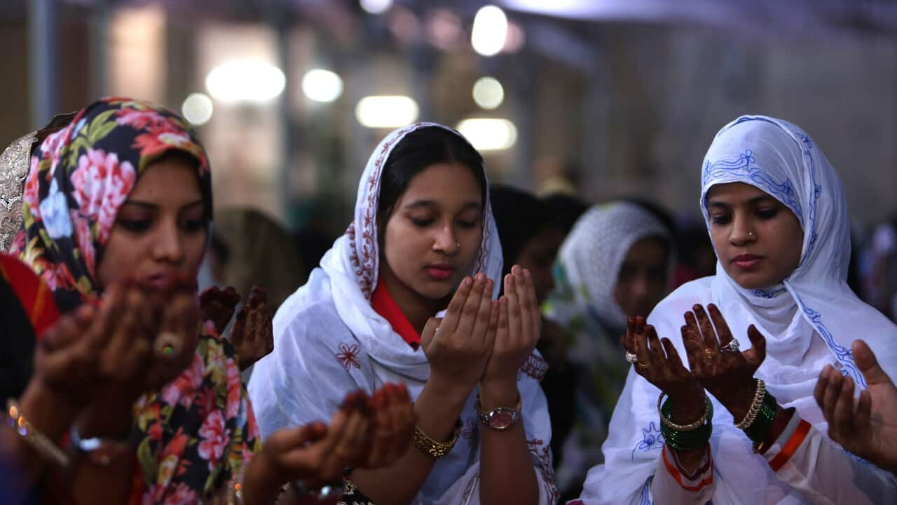 Three women wearing hijab and holding their hands in front of their faces