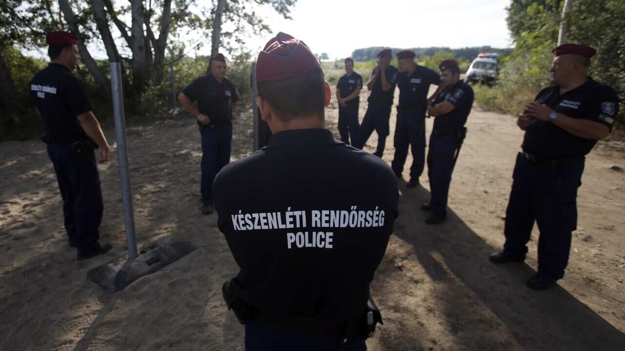 Hungarian police officers guard the area where work has begun on a 150 meter fence near Morahalom, Hungary, Monday, July 13, 2015. Hungary has begun building a fence on the country's southern border with Serbia.