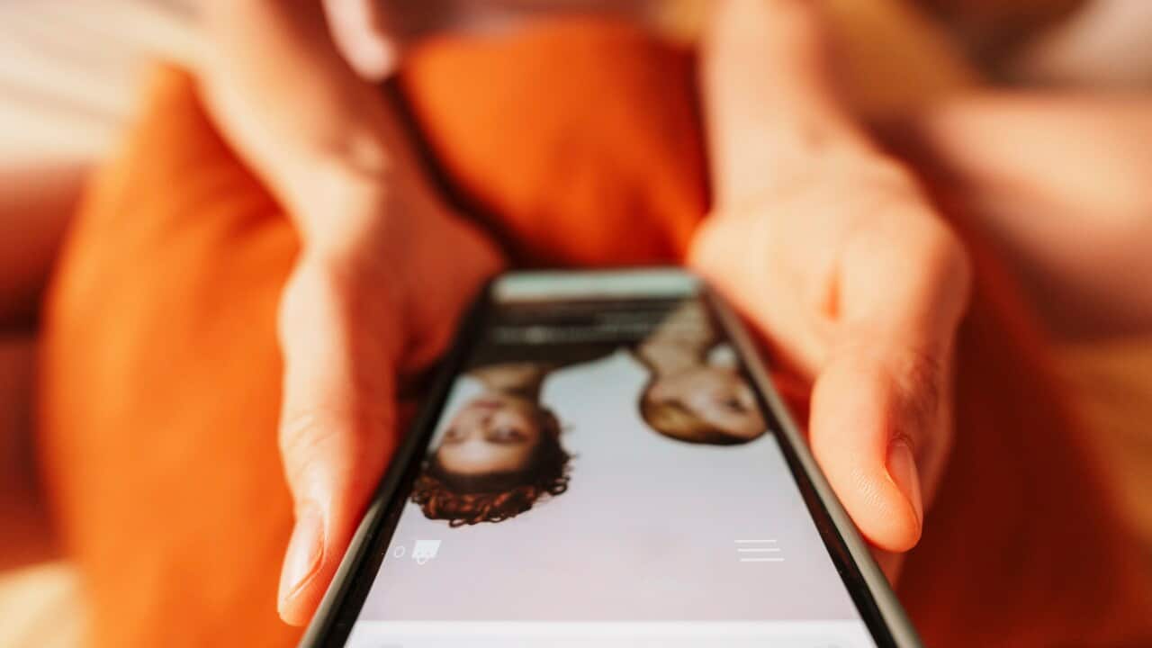 Hand holding smartphone shopping online at home in casual setting