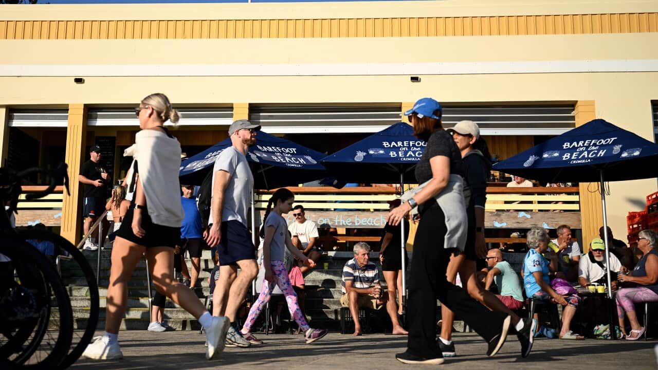People walking past a cafe on the foreshore.