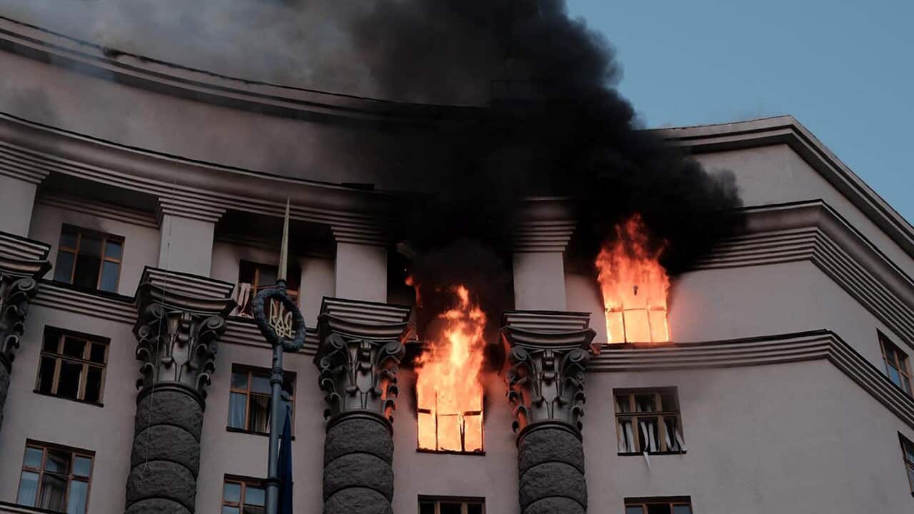 Flames burst out from the windows of a building on fire.