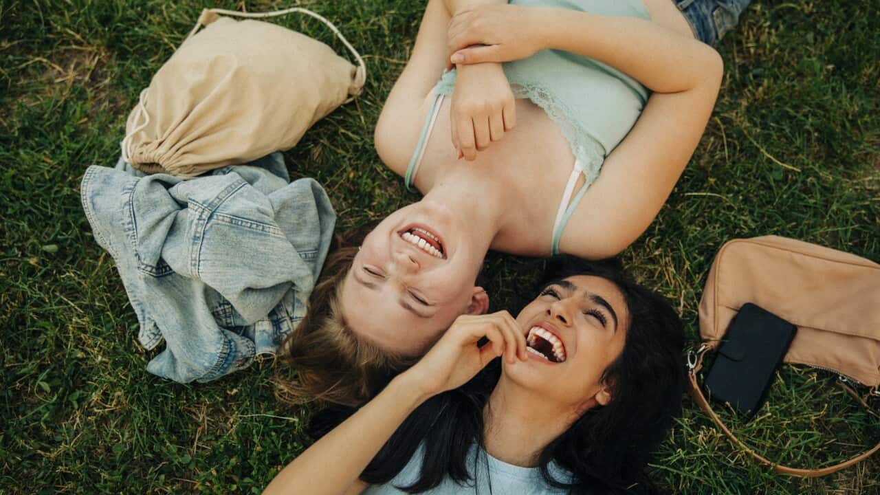 Cheerful teenage girls lying together at park