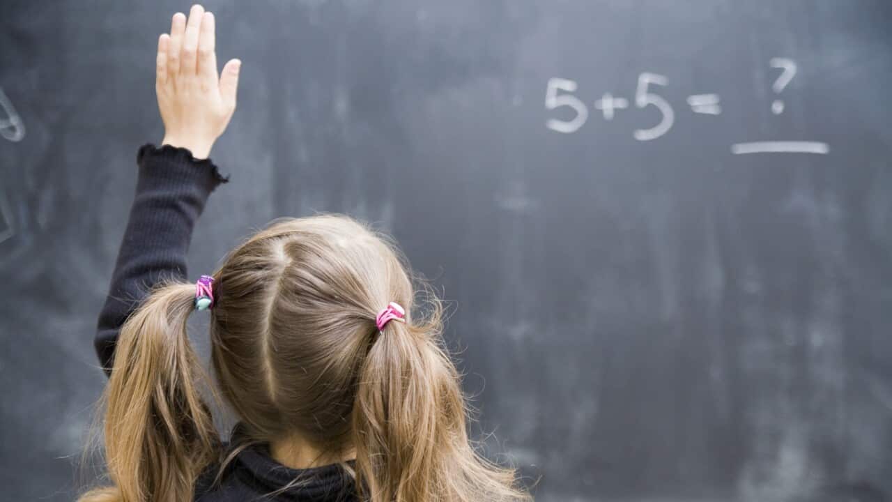 Girl in classroom with raised hand