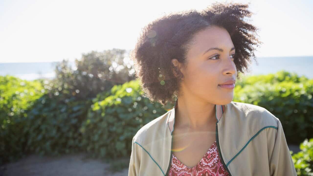 Pensive young woman looking away at sunny beach
