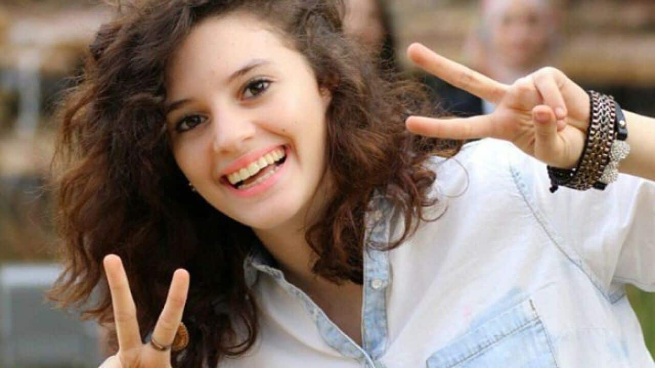 A young woman smiling and making peace symbols with her fingers. 