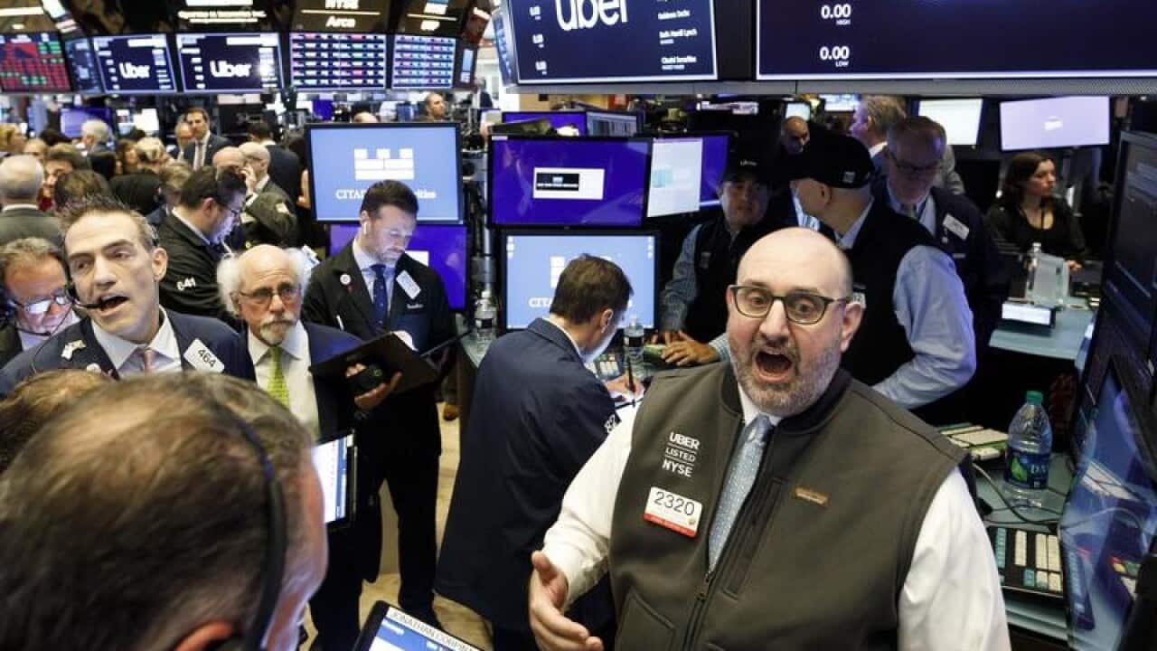 Traders on the floor of the NYSE listen for pricing information