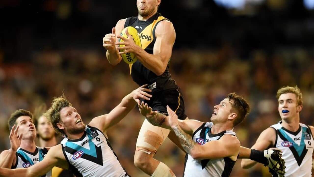 Shaun Hampson of the Tigers leaps over Power players.