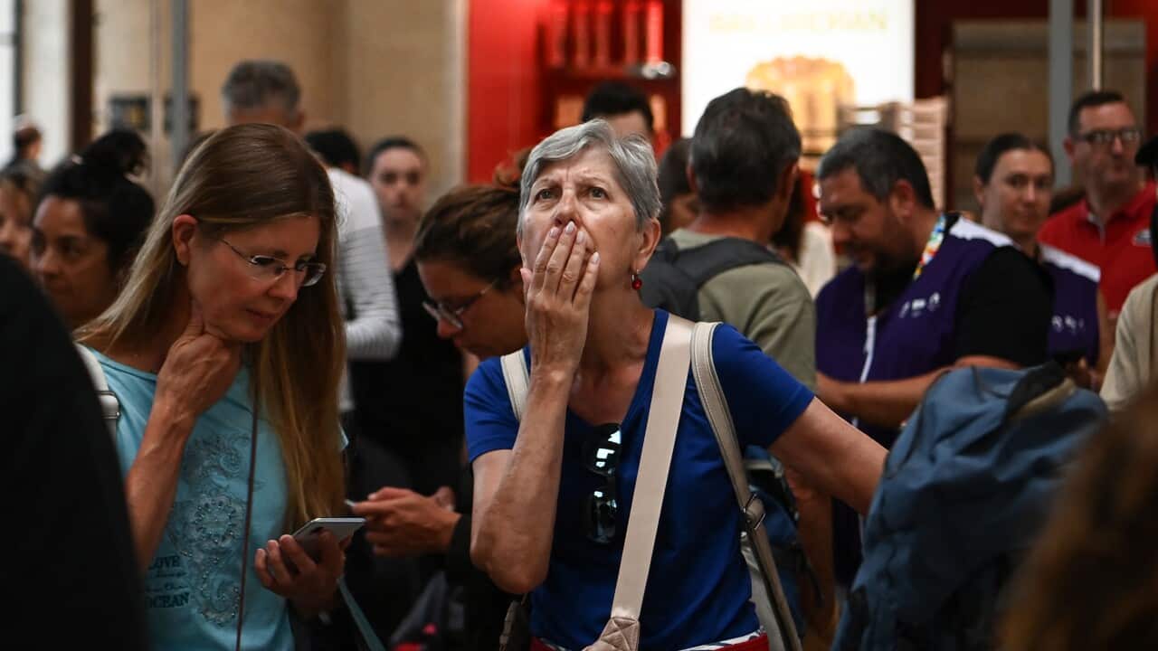 A woman looks at an information screen as passengers wait for their train departures.