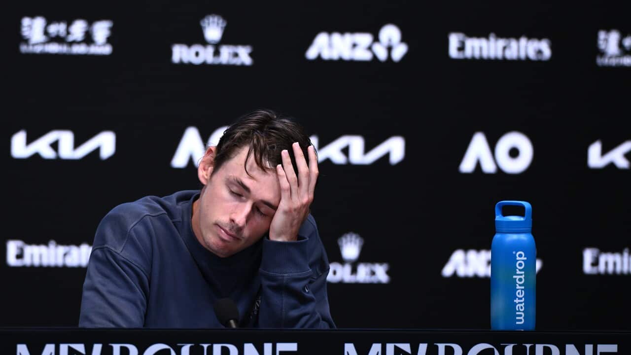 A young white man with his hand on his face