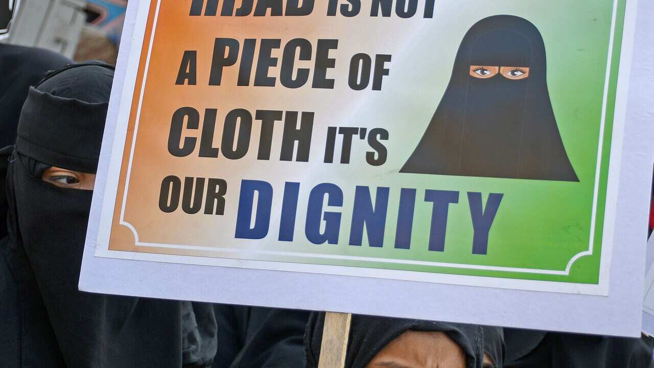 Eine muslimische Frau, die einen Hijab trägt, hält während einer Protestaktion ein Plakat hoch