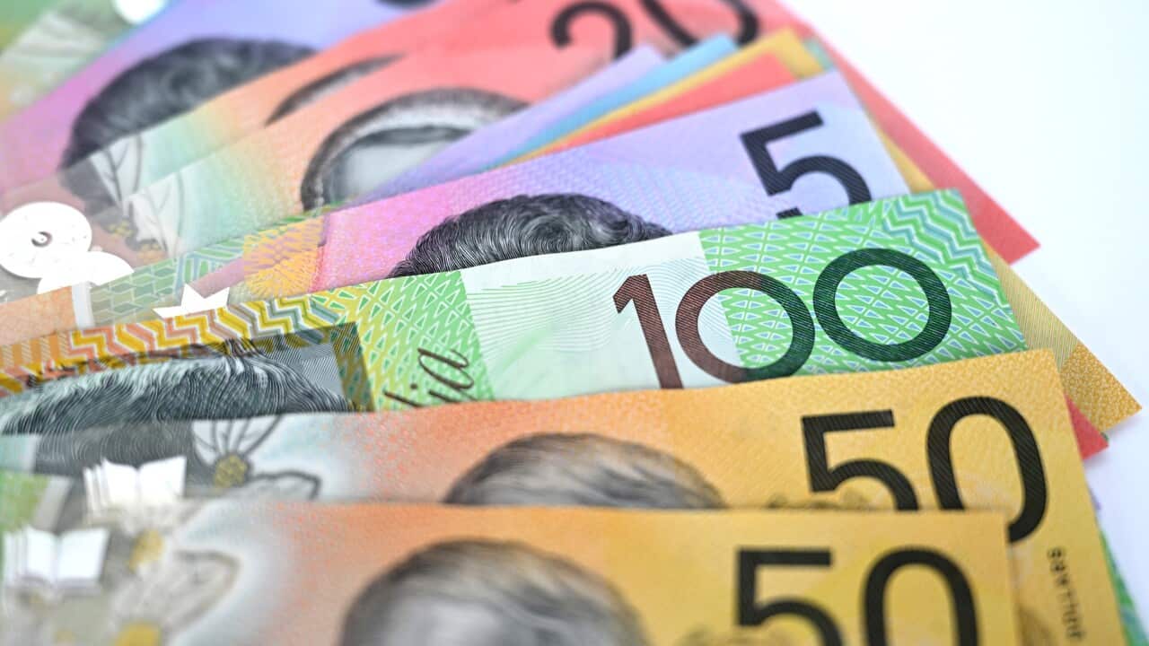 Australian currency in bank notes splayed out on a white table. The two fifty dollars notes in the foreground.