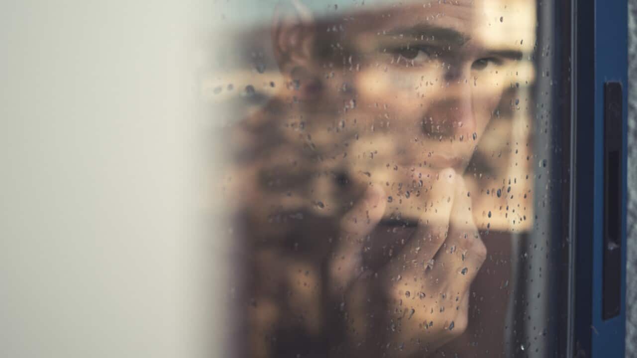 Depressed man looking through window
