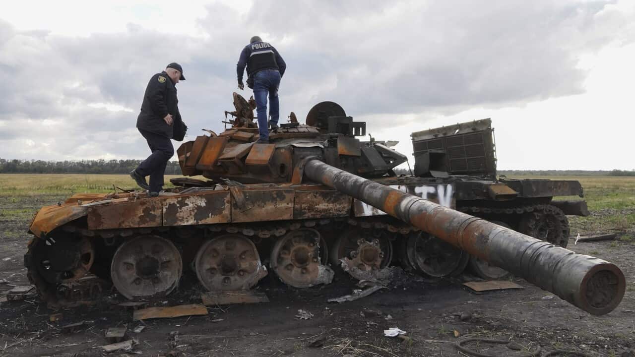 Ukrainian policemen inspect a damaged Russian tank near the recently recaptured city of Kupyansk in Kharkiv. (AAP)