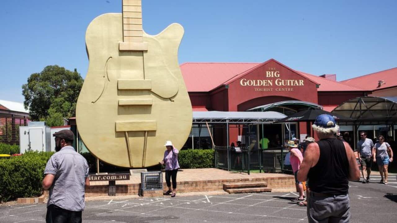 Festival goers pose for photos outside the Big Golden Guitar at the 46th Tamworth Country Music Festival in Tamworth - AAP B Esposito