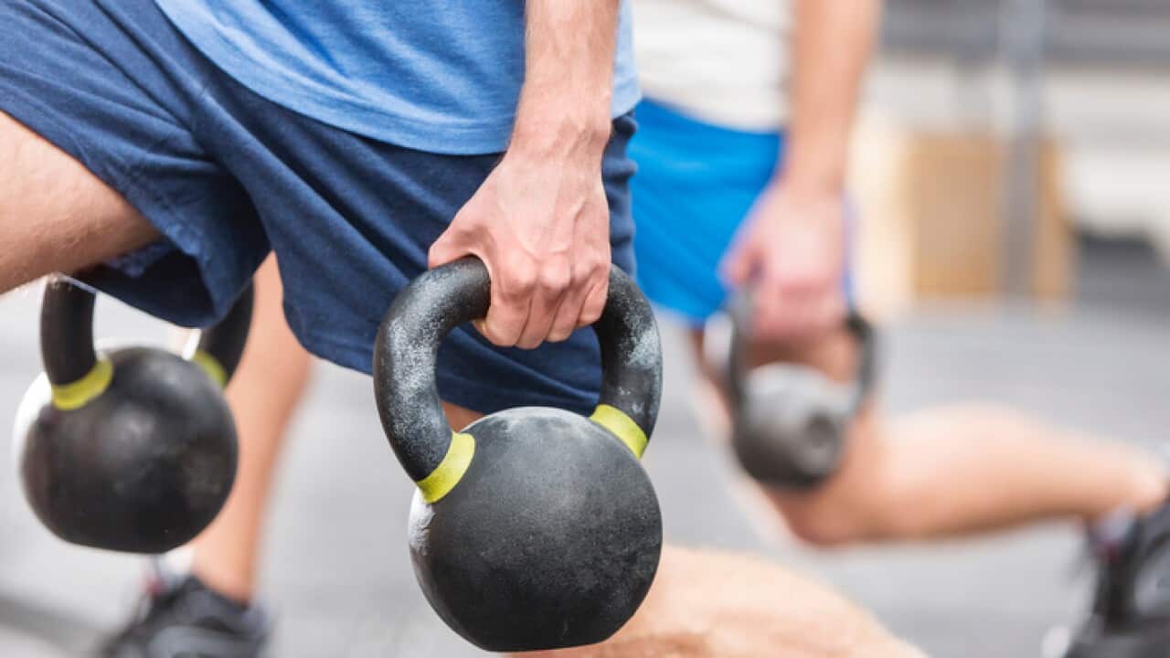 Cropped image of men lifting kettlebells at crossfit gym
