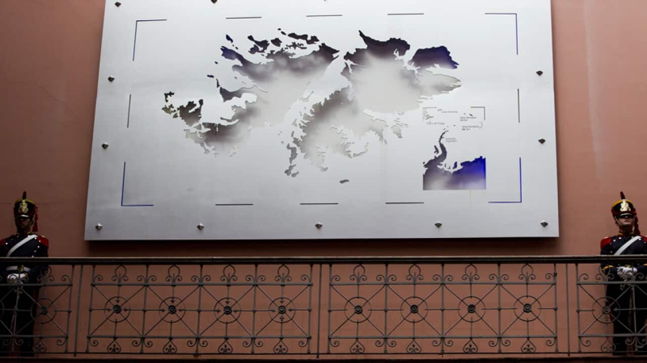 Soldiers stand next to a map of the Falkland Islands