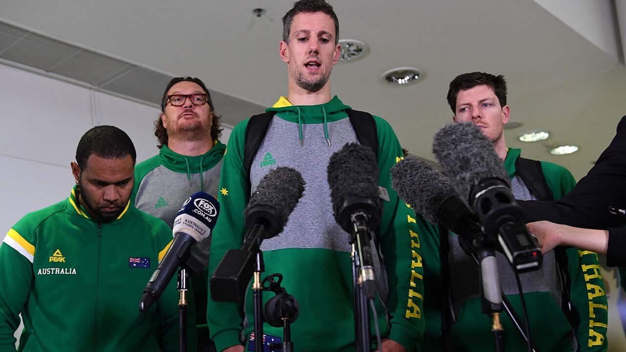 Daniel Kickert of the Boomers, the Australian national basketball team (centre), speaks to the media as he arrives at Brisbane airport, Wednesday, July 4, 2018