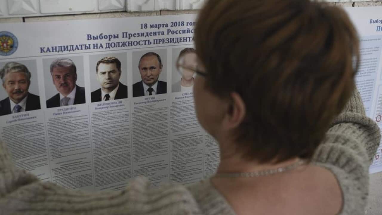 A polling station official hangs a list of candidates