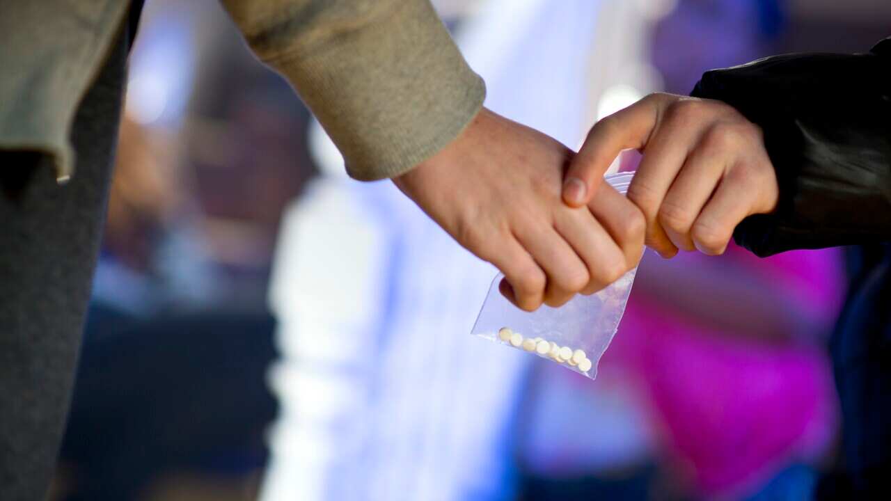 Hands passing over a bag of pills