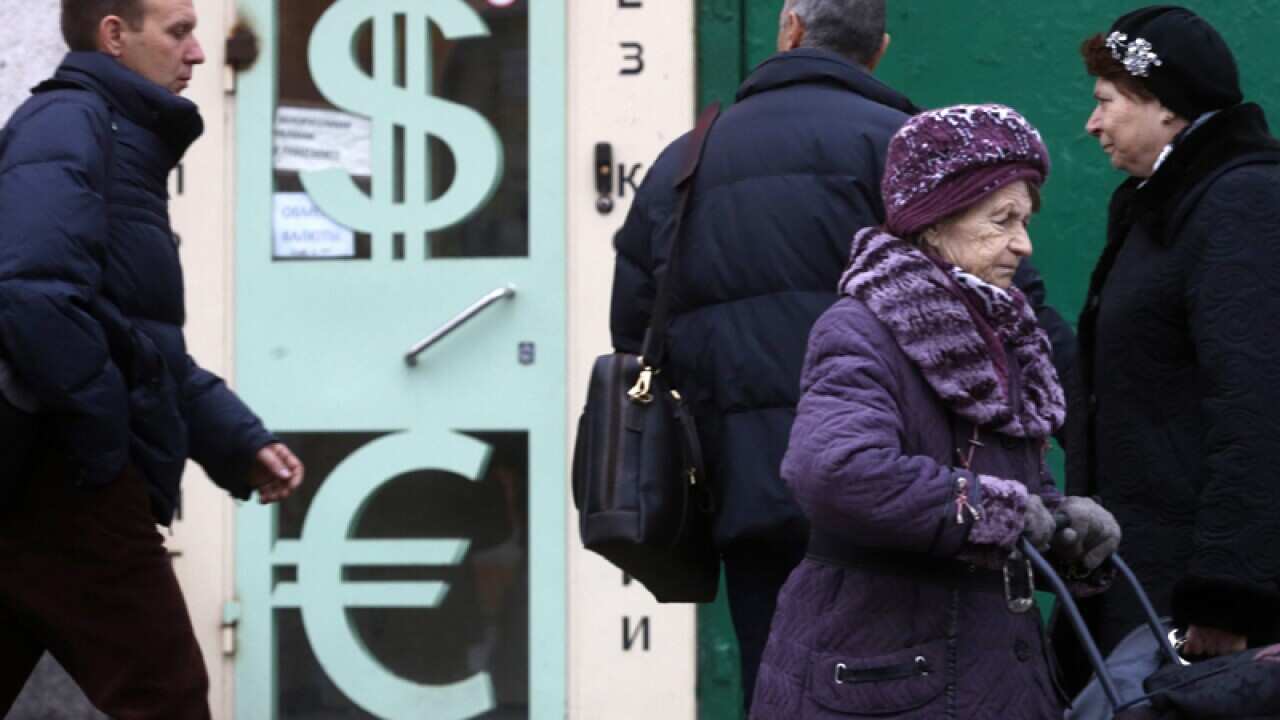 Pedestrians walk past a foreign exchange booth in Moscow