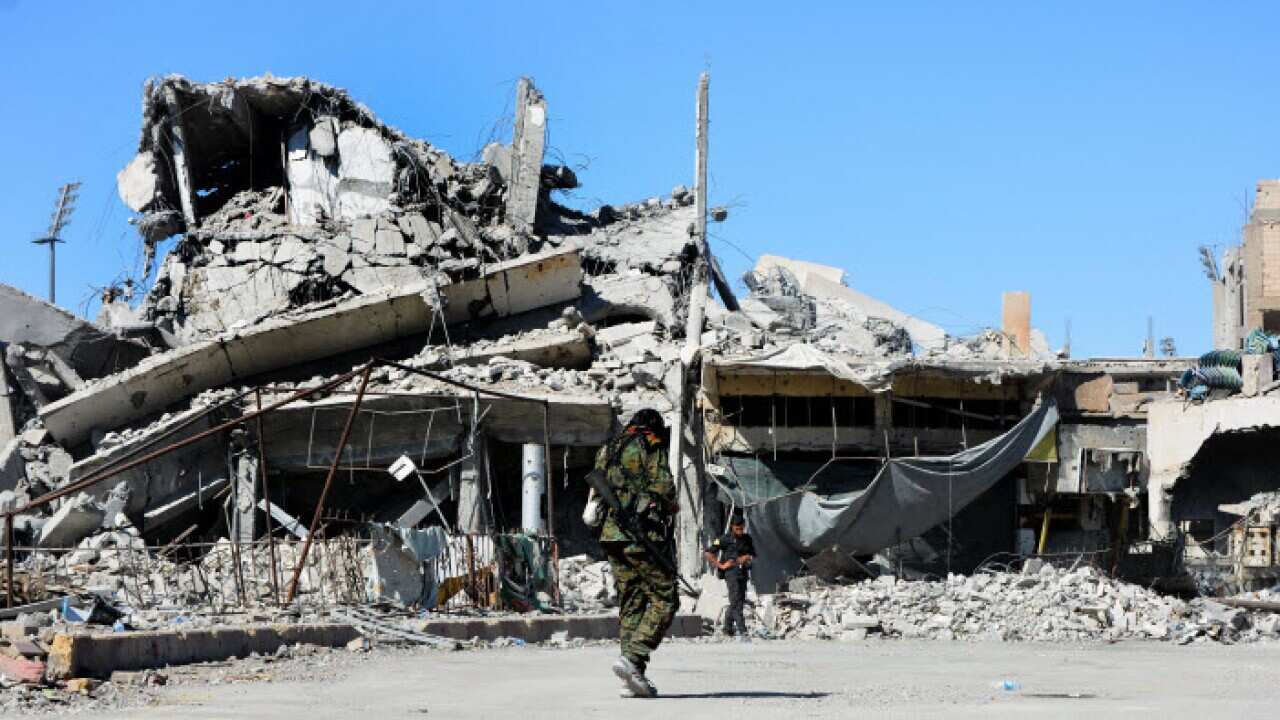A fighter from the Syrian Democratic Forces (SDF) walks near the Al-Na'im roundabout in central Al-Raqqa, Syria