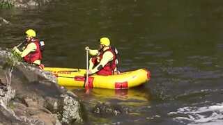 Two rescuers rowing a rescue canoe on a river