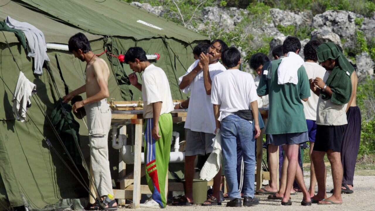 In this file photo men shave, brush their teeth and prepare for the day at a refugee camp on the Island of Nauru.