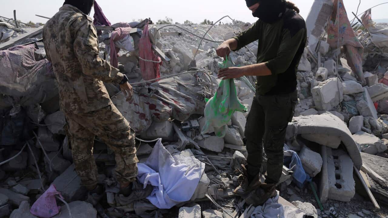 People look at a destroyed houses near the village of Barisha, in Idlib province, Syria,