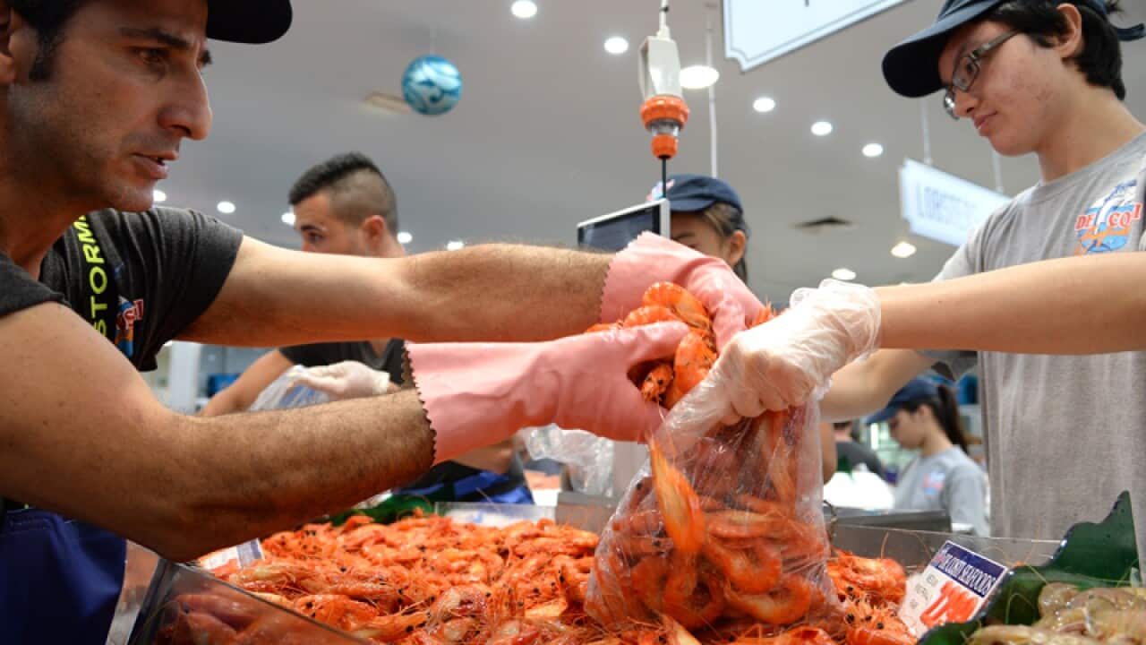 A fish market worker packs prawns for customers