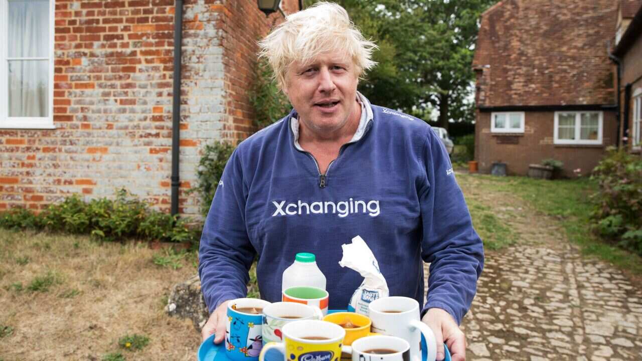 Boris Johnson brings tea for the press to drink outside his house in Thame.. Picture date: Sunday August 12, 2018. 