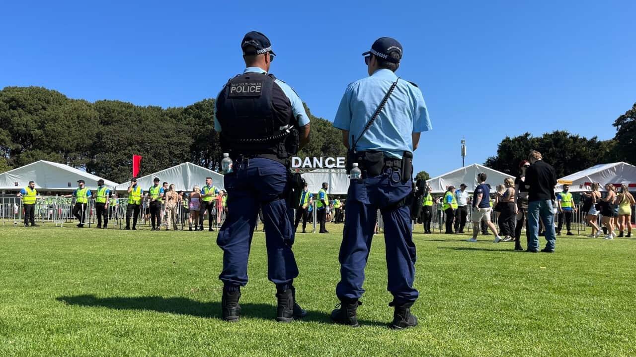 Police officers observe teens entering security lines at a festival.