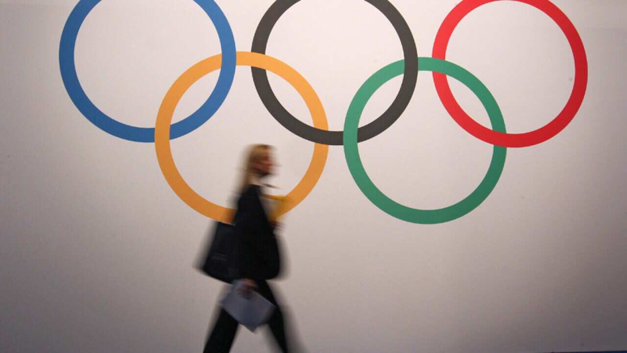 A woman walks past the Olympic Rings