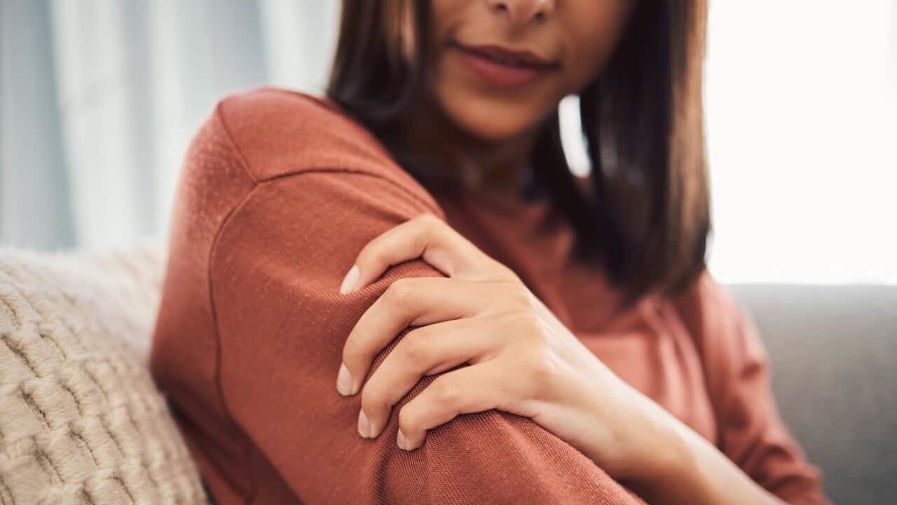 Close up of a young woman holding her arm and suffering with pain