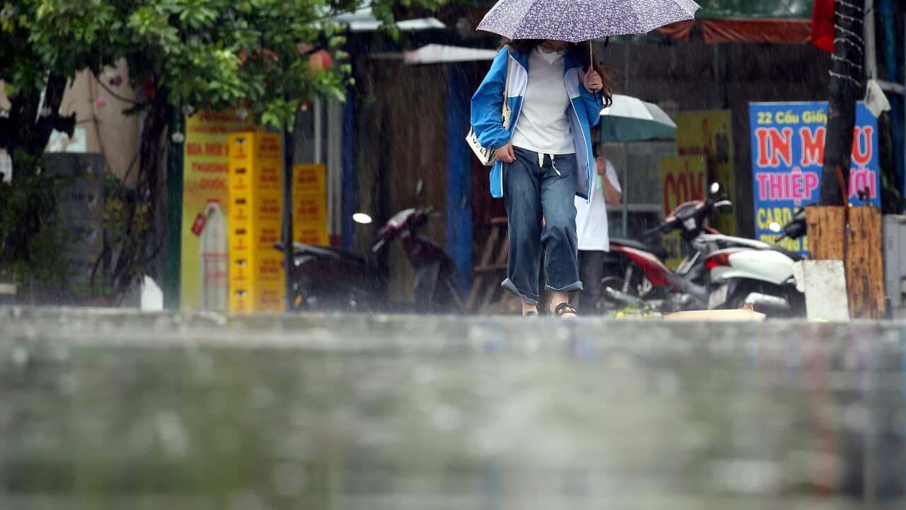A woman holding an umbrella walks under the rain.