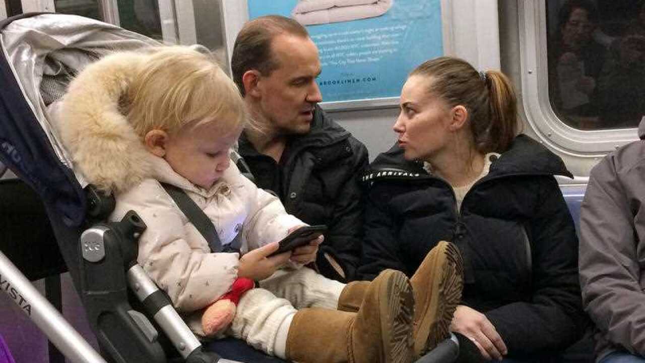 In this Dec. 17, 2017, photo, a baby girl plays with a mobile phone while riding in a New York subway. 