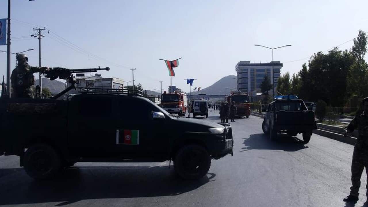 Afghan security officers inspect the scene of a suicide attack.